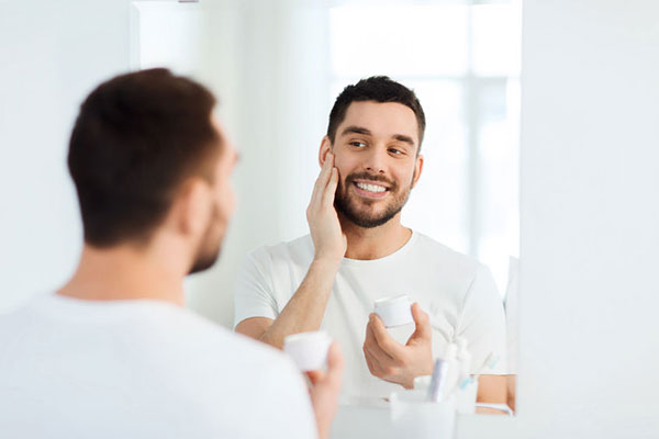Young man applying face lotion - learn how prebiotic and probiotic materials can be use in skin care formulations in the Prospector Knowledge Center.