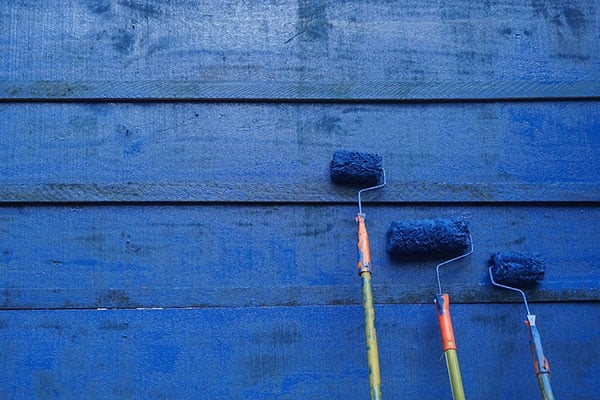 Paint rollers on blue painted wall - learn about how to lower VOCs in paint formulations in the Prospector Knowledge Center.