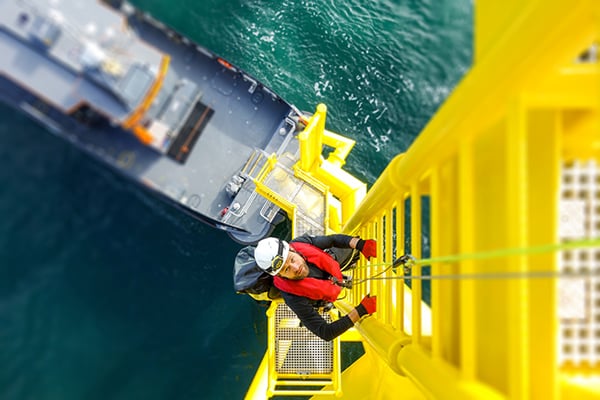 Man climbing on wind turbine offshore - Learn about coatings for sustainable resources