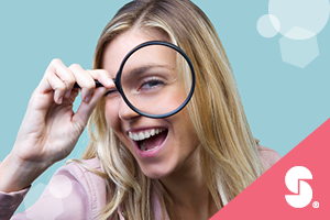 Smiling woman looking through a magnifying glass