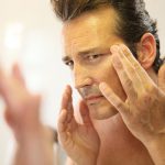 man applying face cream- learn about male skin and hair care product formulations