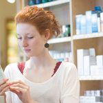 Lady reading cosmetics label - Learn more about cosmetic expiration dates