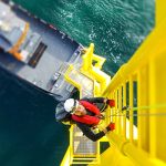 Man climbing on wind turbine offshore - Learn about coatings for sustainable resources
