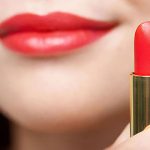 Model wearing and holding red lipstick