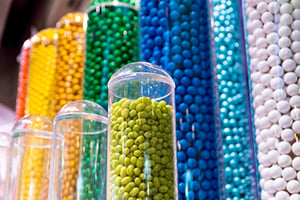These collections of jellybeans, gumballs, and other candies are for sale in a toystore.  This very colorful display used clear acrylic tubes to hold all the candy.